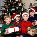 Joyful children celebrating Christmas with gifts by tree