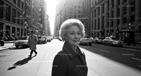 Elderly Woman in Busy City Street Surrounded by Vintage Cars