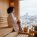 Serene Woman Sitting in Sauna with City View Behind