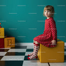 Thoughtful little girl in red dress sitting on yellow cube
