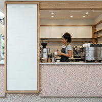 Barista preparing coffee behind modern terrazzo counter