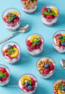Fresh berry and yogurt parfaits arranged on blue surface