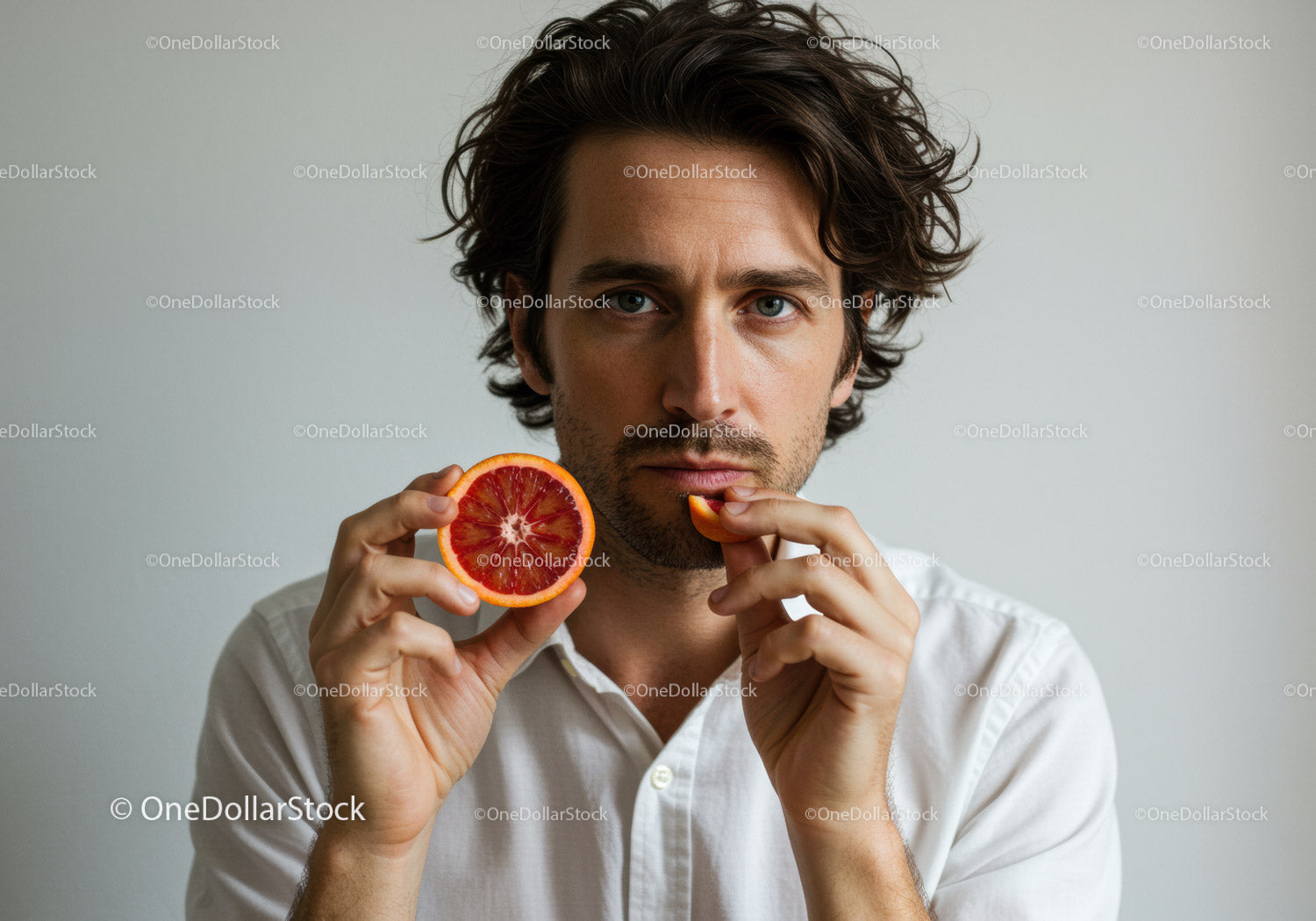 Young Man Holding Bright Red Blood Orange in Minimalist Portrait