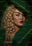 Glamorous Woman with Curly Blonde Hair Among Tropical Leaves