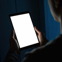 Person Holding Bright Tablet in Dark Indoor Setting