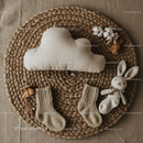 Cozy neutral baby items arranged on woven mat