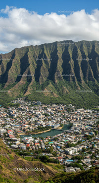 Lush Green Mountain Range Over a City with River Under Bright Sky