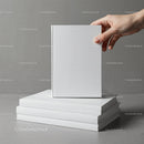 Hand Holding Blank White Book Over Stacked Books