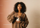 Portrait of a Woman with Curly Hair Holding a Beige Ceramic Pitcher in Cozy Home Setting