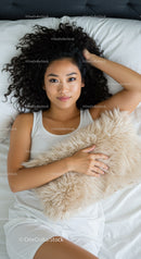 Young woman relaxing on bed with cozy fluffy pillow