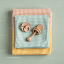 Stack of soft pastel baby blankets with pacifiers