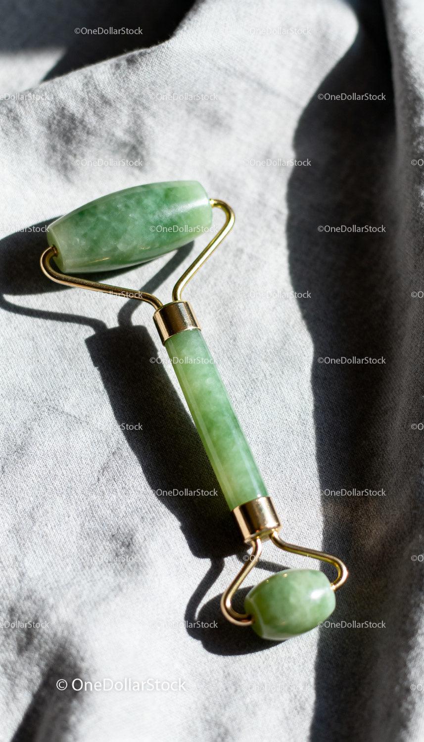 Natural jade facial roller on soft fabric background