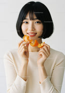 Portrait of a Happy Young Woman Holding a Tangerine Peel in Bright Studio