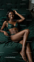 Smiling woman relaxing on dark green bed linen
