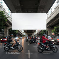Busy Urban Street with Motorcycles and Traffic Under Overpass