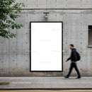 Urban man walking past blank vertical billboard on wall