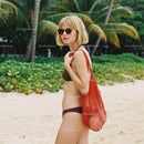Stylish Woman in Bikini with Red Mesh Bag on Tropical Beach