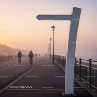 Early Morning Cyclists on Misty Waterfront Path