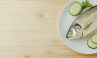 Fresh Whole Fish with Cucumber Slices on White Plate for Seafood Cuisine