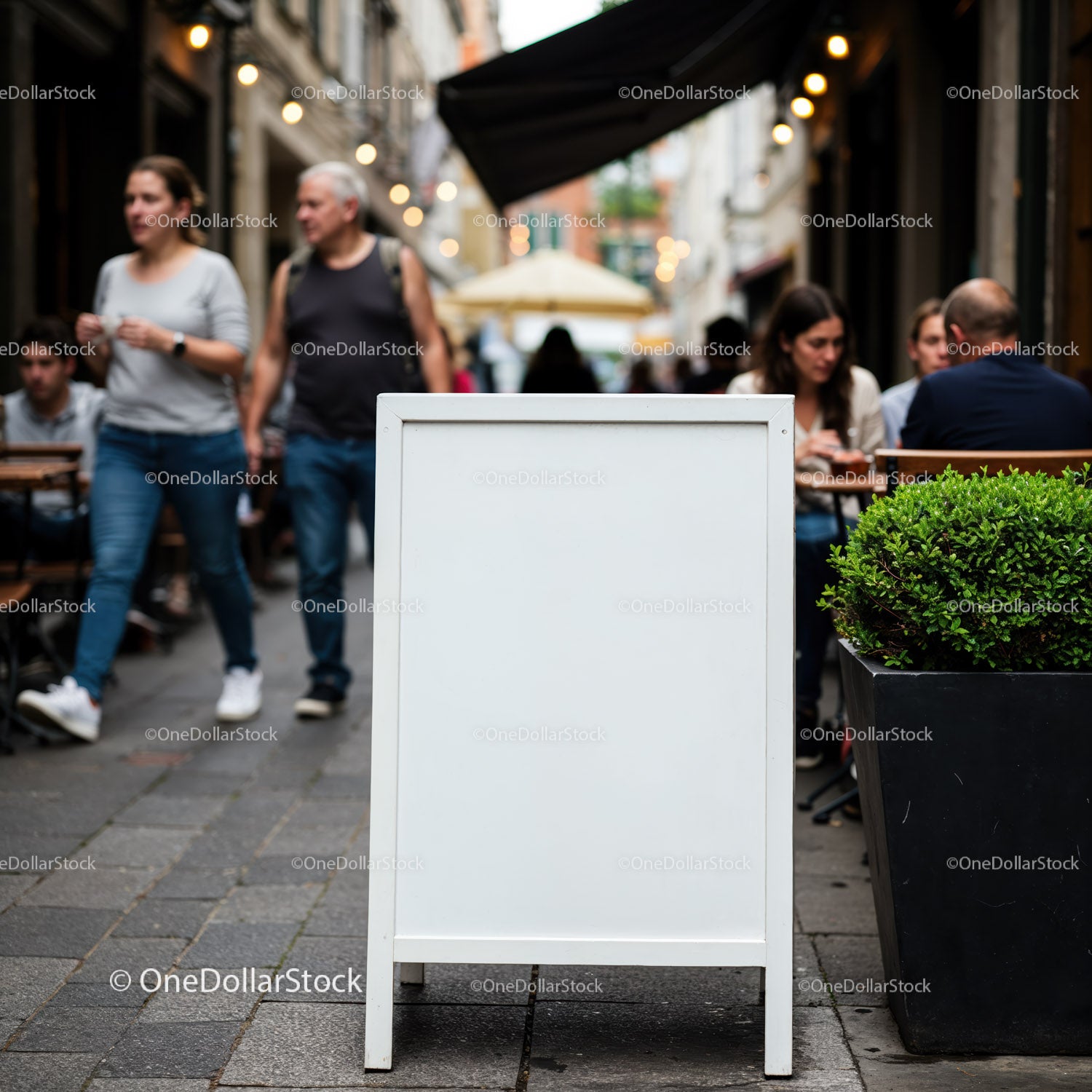 Blank sidewalk sign outside bustling city cafe
