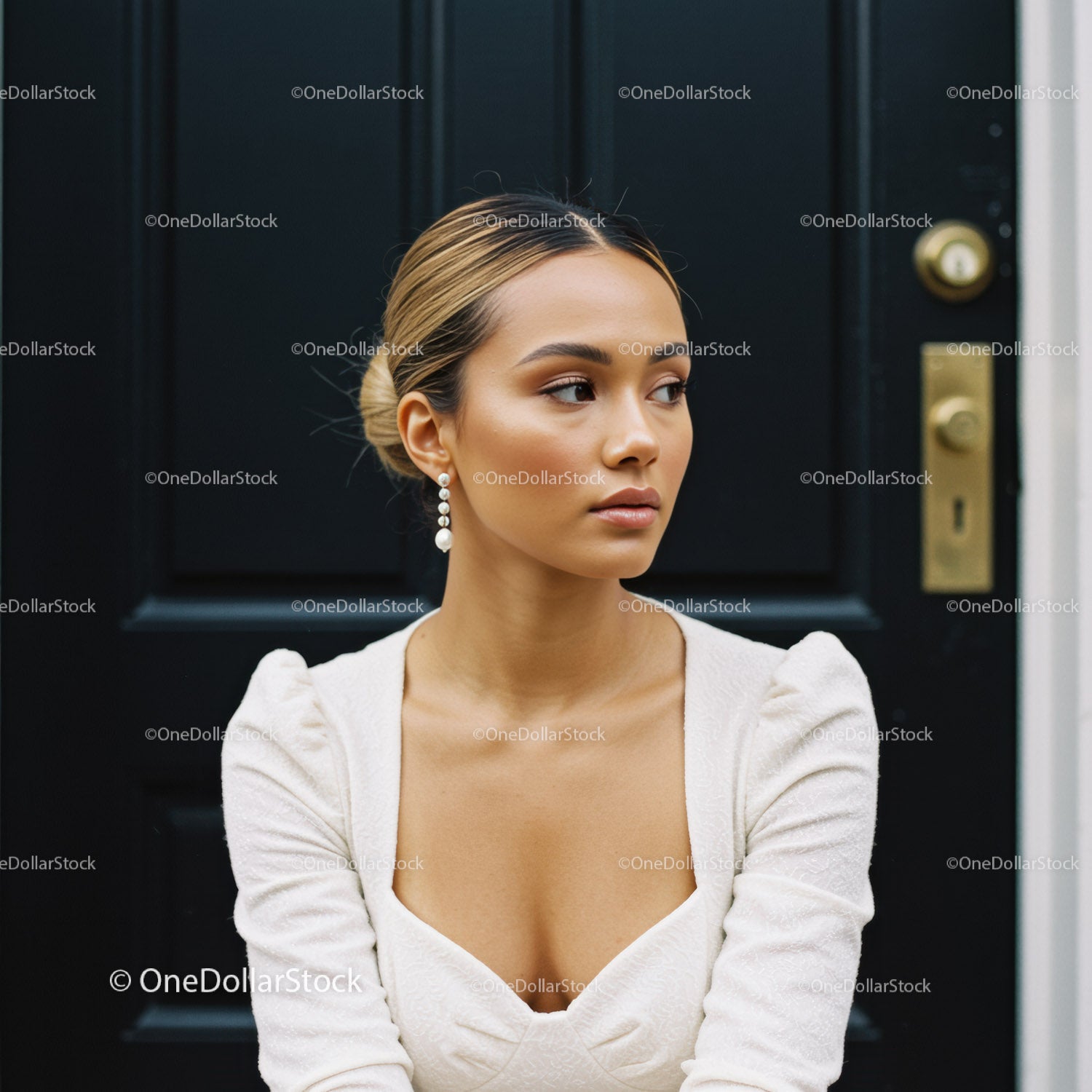 Elegancka kobieta w białej sukni siedząca przy czarnych drzwiach