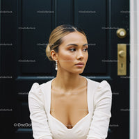Elegant woman in white dress sitting by black door