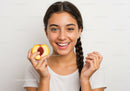 Young Girl Smiling and Holding a Peach Slice in Bright Indoor Setting