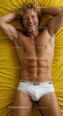 Smiling man relaxing on yellow bed in white underwear