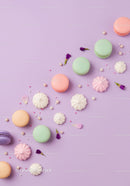 Assorted pastel macarons and meringues on lilac background