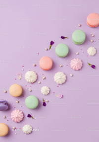 Assorted pastel macarons and meringues on lilac background