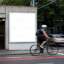 Cyclist passing by blank urban billboard on city street