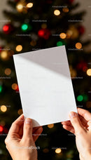 Hands Holding Blank Card Against Festive Christmas Tree Lights JPG Mockup Image preview