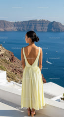 Woman in pale yellow dress overlooking blue ocean view