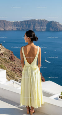 Woman in pale yellow dress overlooking blue ocean view
