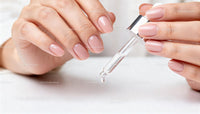 Close-up of hands applying nail serum with dropper
