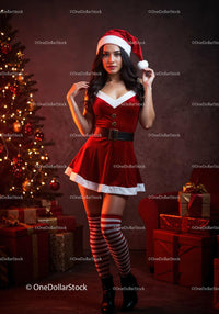 Young woman in festive Santa outfit by Christmas tree