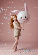 Red-haired girl holding bunny face balloon with confetti
