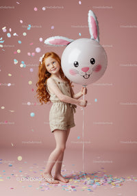 Red-haired girl holding bunny face balloon with confetti