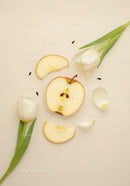 Fresh apple slices with white tulips on beige background