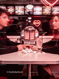 Couple Holding Hands in Retro Diner with Neon Heart