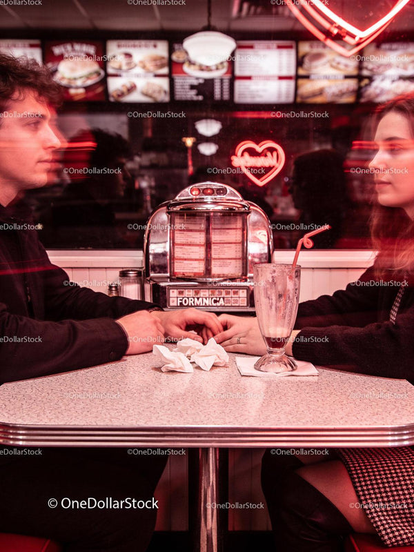 Couple Holding Hands in Retro Diner with Neon Heart