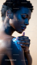 Woman Applying Cream to Her Shoulder in Soft Light