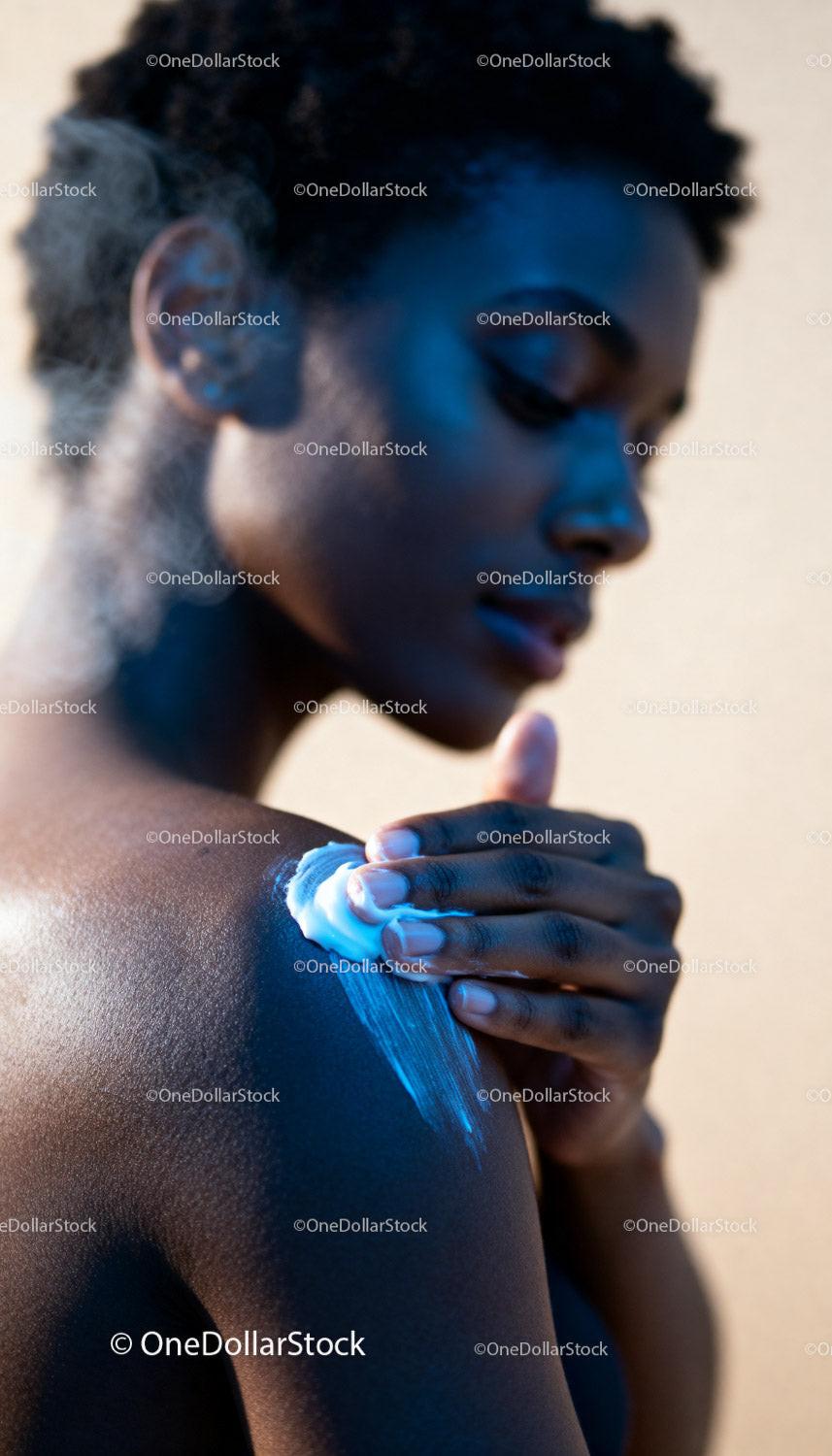 Woman Applying Cream to Her Shoulder in Soft Light