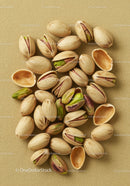 Close up of open pistachio nuts on beige fabric