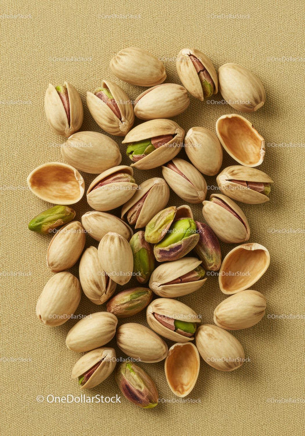 Close up of open pistachio nuts on beige fabric