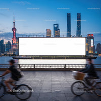 Evening cityscape with cyclists and large billboard by river