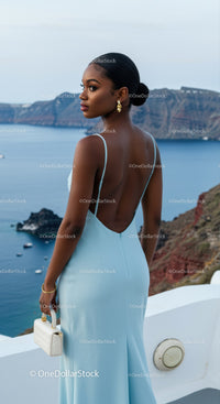 Elegant woman in blue dress overlooking coastal cliffs