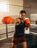 Focused Female Boxer Throwing Punch in Training Gym