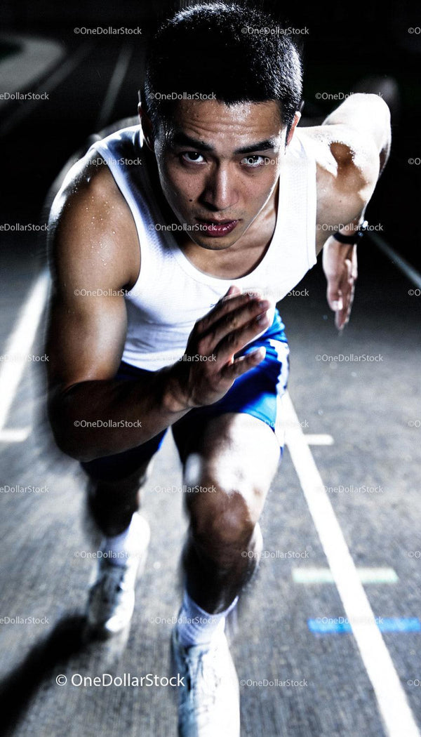 Focused male sprinter pushing off during intense night training