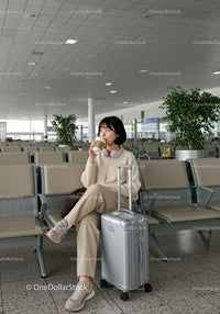 Young Woman Drinking Coffee in Airport Lounge With Luggage